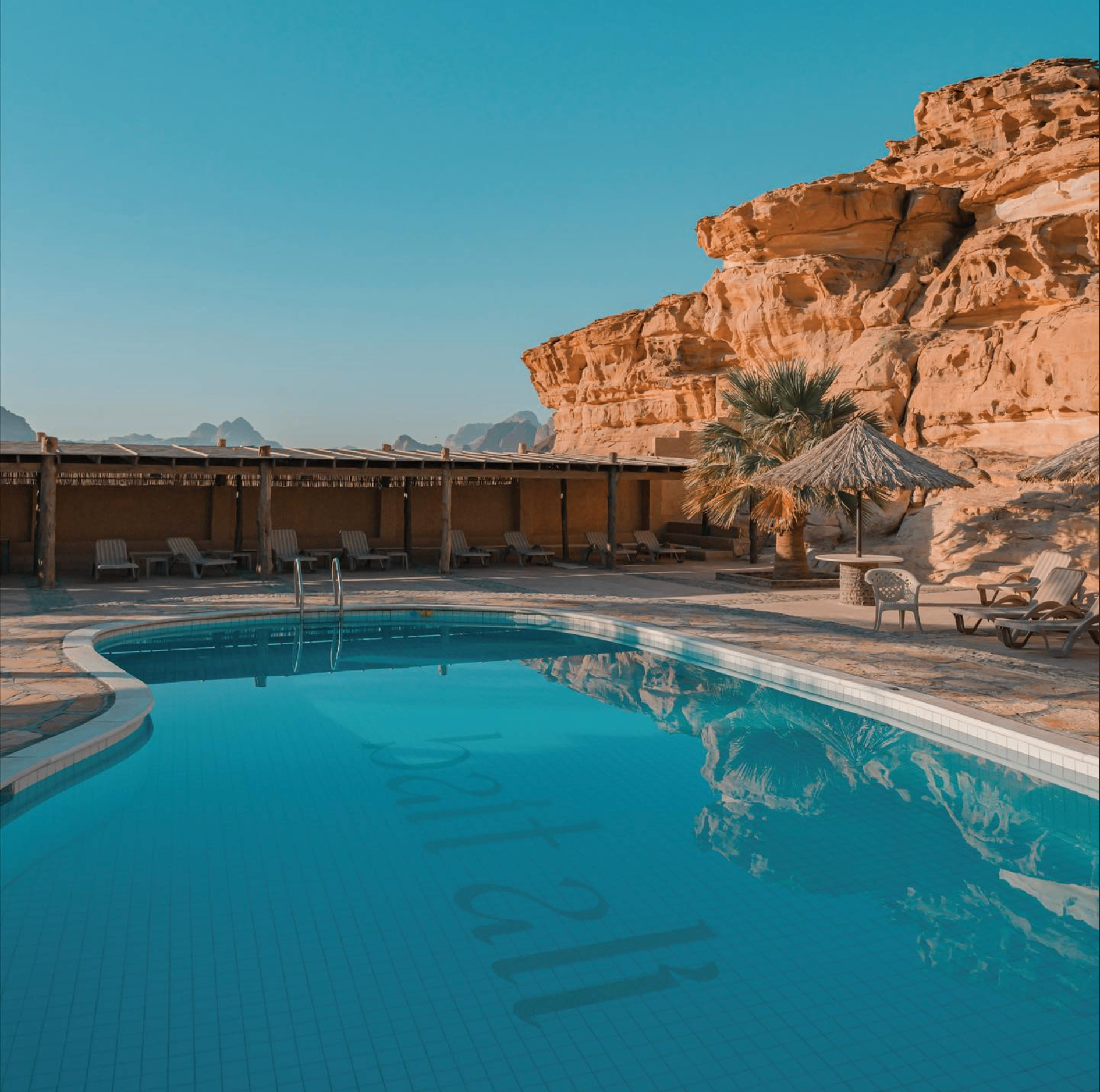 Lodge swimming pool reflecting Wadi Rum cliffs